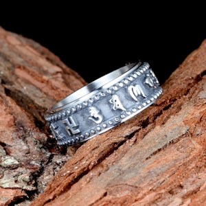 Bague vintage en acier titane avec symboles religieux gaufrés sur fond en bois