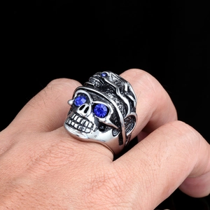 Détail macro d'une bague tête de mort gothique avec yeux en pierres bleues sur main
