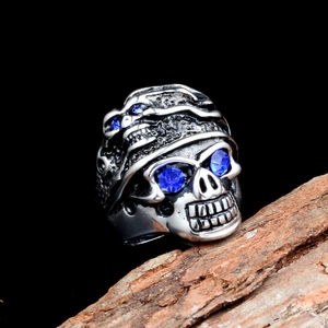 Bague tête de mort vintage en acier avec yeux en cristal bleu sur fond bois