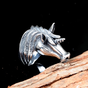 Close-up of vintage unicorn head ring with detailed engraving on rustic bark