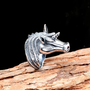 Vintage stainless steel unicorn ring with intricate carvings on natural wood background