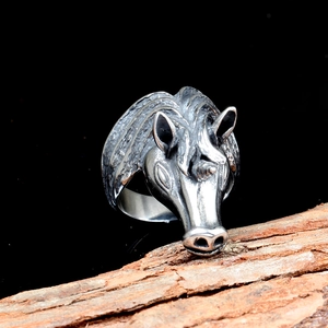 Vintage stainless steel unicorn animal ring with detailed carvings on a wood bark base