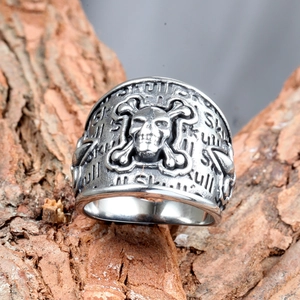 Rugged vintage silver stainless steel skull crossbones punk ring for men shown on bark