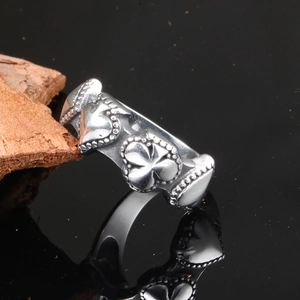 Detail of silver titanium steel ring with clover heart relief and punk bead edges
