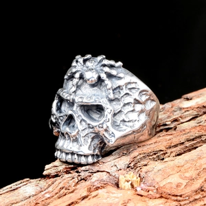 Anillo de calavera gótica con motivo de araña sobre fondo de madera rústica