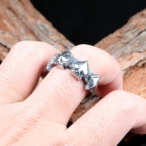 Detail of silver stainless steel ring with poker suit relief on a wooden background