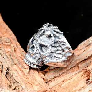 Primer plano de anillo gótico de calavera con araña sobre fondo de corteza de madera