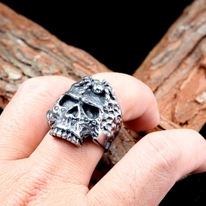 Vista macro de un anillo de calavera gótica con detalle de araña en fondo de madera