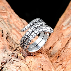 Detailed close-up of a silver snake-shaped stainless steel ring on tree bark background
