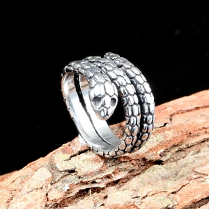 Macro shot of stainless steel snake ring with realistic scale texture on bark