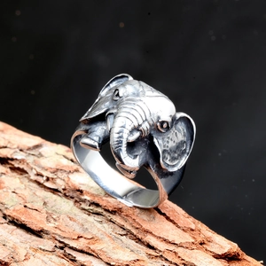 Vintage stainless steel elephant ring with detailed carvings on natural bark background