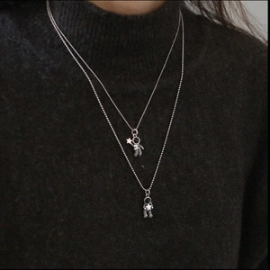 Detail view of astronaut necklaces with star charm on black sweater background
