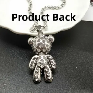 Détail du dos du pendentif ours argenté avec motif trèfle ajouré sur une chaîne à perles