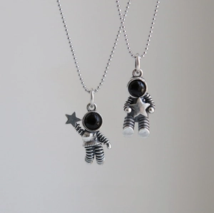Detail of vintage astronaut pendants with star motifs and black enamel masks on bead chains
