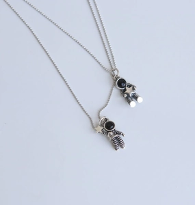 Detailed view of silver astronaut pendants with star motifs on beaded chains
