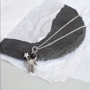 Detail of creative astronaut pendant holding a star with vintage metallic finish