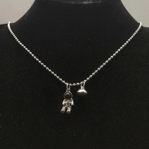 Detailed close-up of a silver astronaut pendant necklace on a black velvet display