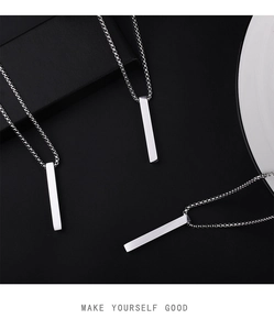 Macro detail of three minimalist polished silver column necklaces on black texture