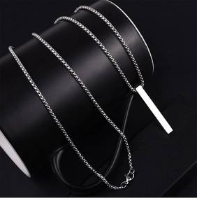 Polished silver bar pendant necklace with sleek box chain displayed on a dark ceramic cup