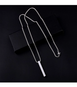 Close-up of a minimalist silver pillar pendant necklace on a black textured jewelry gift box