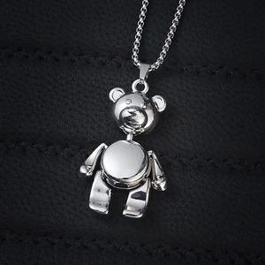 Macro shot of silver mechanical bear pendant with box chain on black leather background