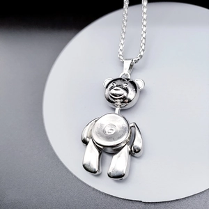 Detailed close-up of a silver movable bear pendant on a woven titanium steel chain