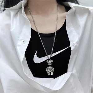 Detailed view of a silver bear pendant necklace worn by a model on a pearl bead chain