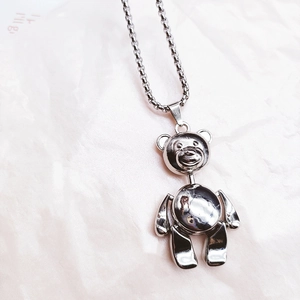 Macro detail of 3D movable bear pendant in polished silver steel on box chain