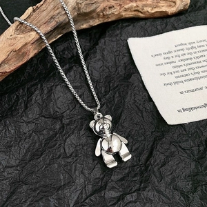 Polished silver bear pendant necklace with movable limbs on vintage background