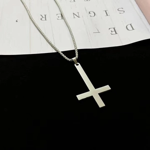 Collier croix inversée en acier inoxydable poli argenté sur fond designer minimaliste
