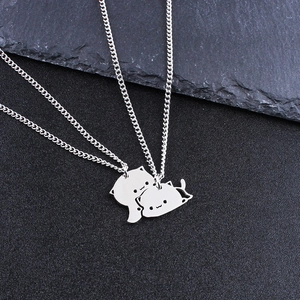 Close-up of interlocking cat pendants on stainless steel necklaces over a black stone base