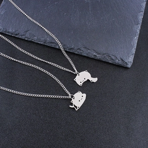 Macro detail of complementary cat puzzle pendants in polished silver stainless steel