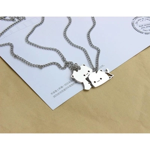 Detailed close-up of matching stainless steel cat pendants on a gift card background
