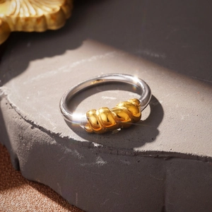 Macro detail of mixed metal silver ring with golden croissant knot on stone base