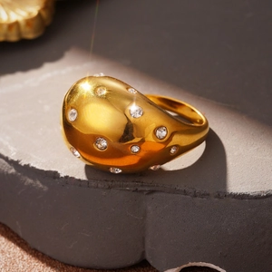 Detailed view of chunky gold dome ring with sparkling zircons on textured stone