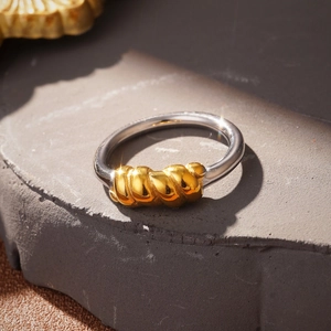 Macro shot of two-tone double layer knotted ring with gold rope detail on silver band