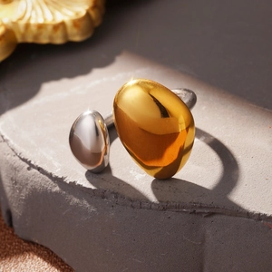Macro shot of two-tone knot ring in polished gold and silver on a textured stone base