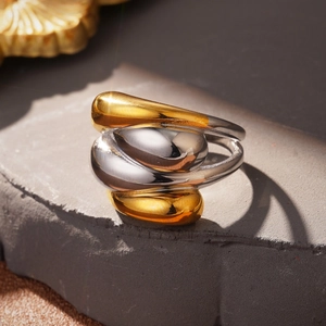 Macro detail of intertwined gold and silver teardrop modules on stone surface