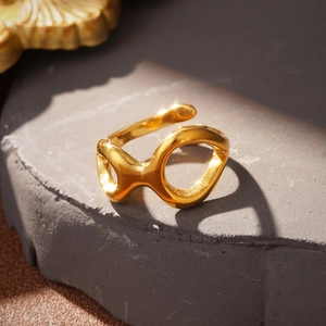 Detailed view of a gold knot ring with a polished organic design on a textured stone base