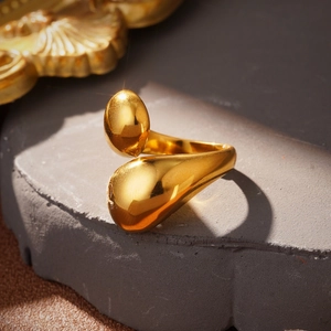 Detailed view of polished gold teardrop ring on stone tray with vintage accents