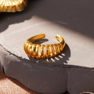 Detailed view of gold knotted hollow ring on grey stone texture background