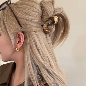 Detail view of amber tortoiseshell hair claw clip used for a half-up hairstyle on blonde hair
