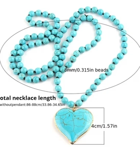Detail of turquoise heart pendant with gold rim on long beaded ethnic necklace