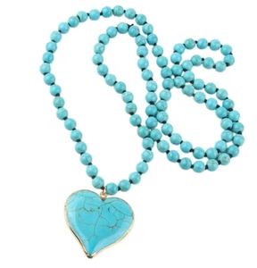 Detailed macro view of the turquoise heart pendant with gold edges and beaded chain