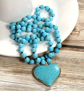 Macro shot of turquoise beaded necklace featuring a large gold-edged heart shaped pendant