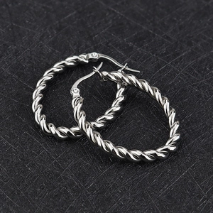 Détail macro de créoles torsadées en argent avec texture tressée fine et fermoir sécurisé