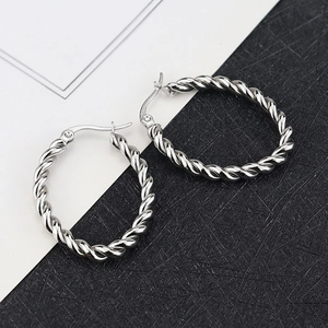 Détail de boucles d'oreilles créoles torsadées argentées avec texture métallique brillante