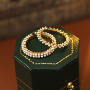 Gros plan de boucles d'oreilles créoles dorées avec doubles rangées de perles