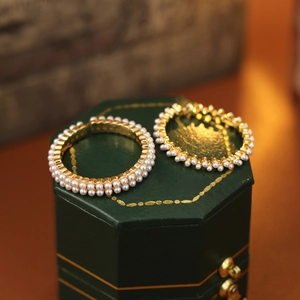 Boucles d'oreilles créoles dorées avec deux rangées de perles sur un écrin vert