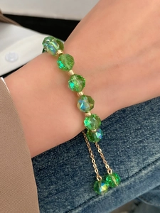 Close-up of green faceted beads and gold spacers on a geometric adjustable bracelet
